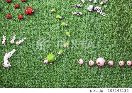 Small ceramic figurines of animals on artificial grass, top view Small ceramic figurines of animals on artificial grass, top view 108148156