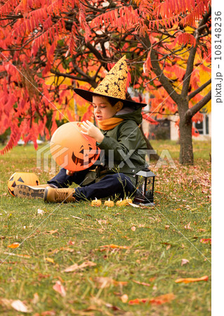 Happy Halloween kid playing with pumpkin balloon in park in autumn. Happy Halloween kid playing with pumpkin balloon in park in autumn. 108148236