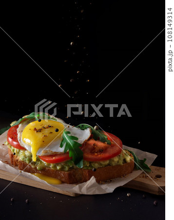 Scrambled eggs avocado tost bruschetta in dark background for breakfast levitation Scrambled eggs avocado tost bruschetta in dark background for breakfast levitation 108149314