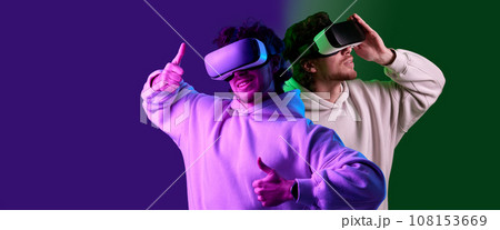 man in vr glasses and sweatshirt plays on blue background. man in vr glasses and sweatshirt plays on blue background. 108153669