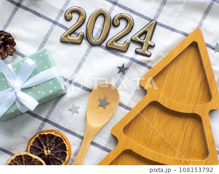 Empty christmas tree shaped wooden plate with 2024 and spoon on towel background 108153792