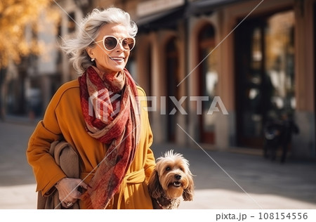 Elderly Spanish woman in stylish autumn dress walks city streets with small dog Elderly Spanish woman in stylish autumn dress walks city streets with small dog 108154556