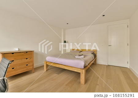a bedroom with white walls and hardwood flooring in the room, there is an empty bed on the right side 108155291