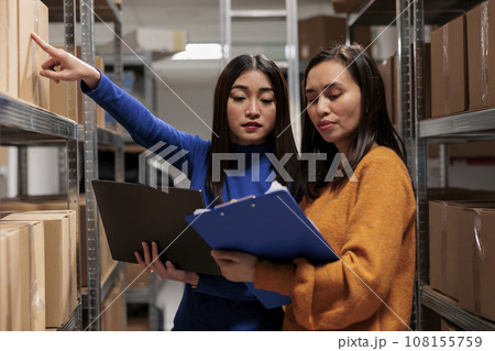 Warehouse worker and supply chain manager tracking inventory in storage room. Storehouse employees planning parcel stocking process optimization, analyzing orders checklist on clipboard 108155759