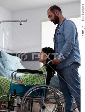 Pregnant woman sitting in wheelchair while future father taking her to maternity room preparing for child delivery in hospital ward. Young couple getting ready for childbirth, discussing parenthood 108156064