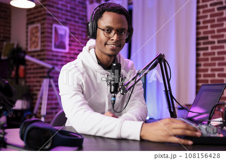 Celebrity vlogger recording internet show with professional camera and sound equipment in living room. Portrait of content creator talking to audiences watching live from home on streaming platform 108156428