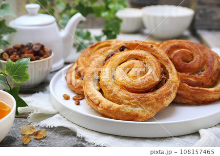 French roll raisin buns, teapot and cup of tea for sweet breakfast 108157465