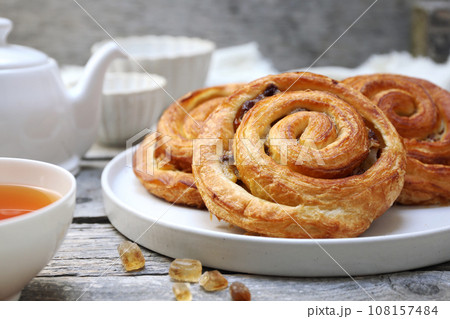 French roll raisin buns, teapot and cup of tea for sweet breakfast 108157484