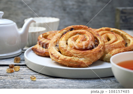 French roll raisin buns, teapot and cup of tea for sweet breakfast French roll raisin buns, teapot and cup of tea for sweet breakfast 108157485