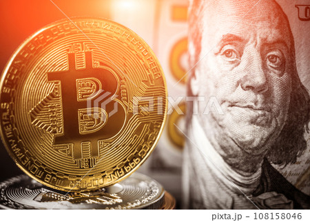 Bitcoin coin standing in front of dollar bills Bitcoin coin standing in front of dollar bills 108158046