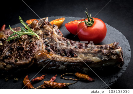 Beef steak with rosemary, chili peeper and tomatoes on slate board 108158056