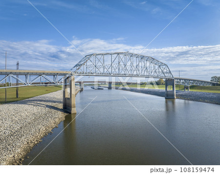 bridges and towboats with barges on Chain of Rock Bypass Canal of Mississippi River above St Louis, aerial view in October scenery bridges and towboats with barges on Chain of Rock Bypass Canal of Mississippi River above St Louis, aerial view in October scenery 108159474