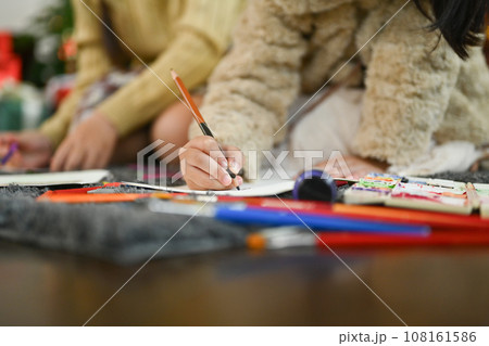Cropped shot of little girl sitting on floor in living room and making Christmas greeting card 108161586