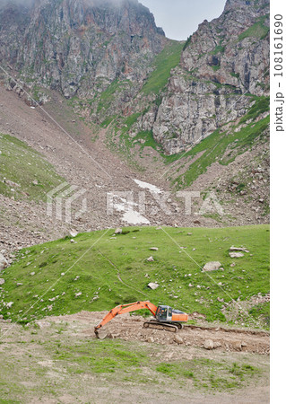 Excavator works in the highlands. Clears the consequences of a mudslide in the gorge of the mountains. repair and expansion of a road 108161690