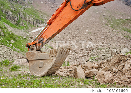 Excavator works in the highlands. Clears the consequences of a mudslide in the gorge of the mountains. repair and expansion of a road 108161696