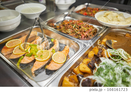 Salmon fillet. Various hot dishes . Glass Showcase in a buffet or self-service restaurant. Salmon fillet. Various hot dishes . Glass Showcase in a buffet or self-service restaurant. 108161723
