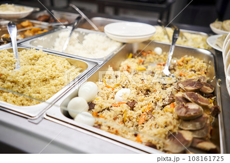 A traditional Uzbek dish called pilaf. Rice with meat, carrots, onions, quail eggs and kazy . Glass Showcase in a buffet or self-service restaurant. 108161725