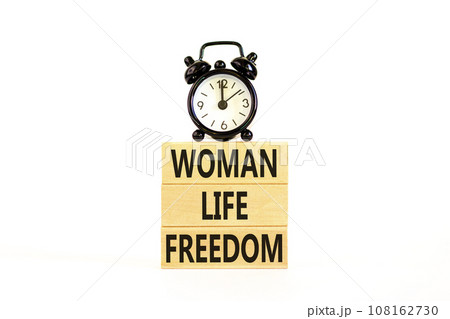 Woman life freedom symbol. Concept words Woman Life Freedom on wooden blocks on a beautiful white table white background. Black alarm clock. Social issue woman life freedom concept. Copy space. Woman life freedom symbol. Concept words Woman Life Freedom on wooden blocks on a beautiful white table white background. Black alarm clock. Social issue woman life freedom concept. Copy space. 108162730