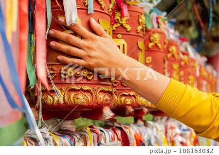 Person pilgrim female hand touching turning spinning Buddhist prayer wheel at Buddhist monastery. Prayer wheels in Buddhist stupa temple. Buddhism religion concept 108163032