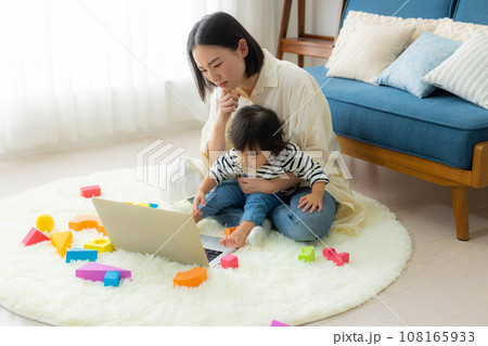 子供を抱っこしながらパソコンを見るお母さん 子供を抱っこしながらパソコンを見るお母さん 108165933