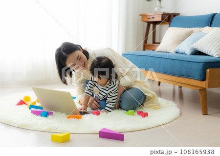 子供を抱っこしながらパソコンを見るお母さん 子供を抱っこしながらパソコンを見るお母さん 108165938