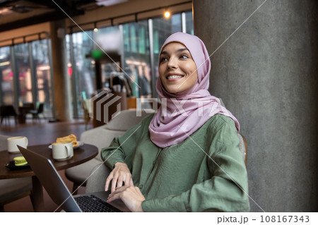 Cute woman in hijab sitting in a cafe and smiling Cute woman in hijab sitting in a cafe and smiling 108167343