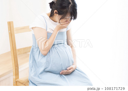 口に手をあてている体調が悪そうな臨月の妊婦女性 108171729