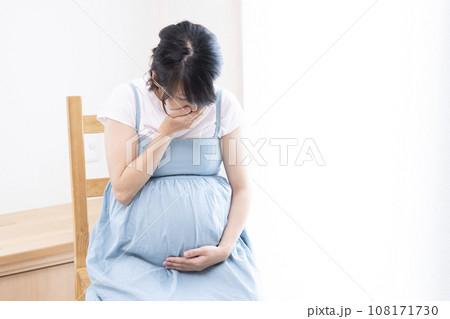 口に手をあてている体調が悪そうな臨月の妊婦女性 108171730