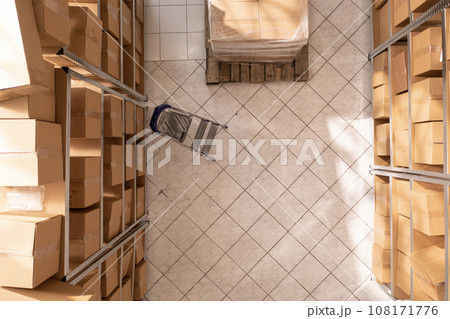 Empty storehouse full with metallic shelves and cardboard boxes, waiting for employee to come and work at customers orders. Storage room with nobody in it ready for packages delivery Empty storehouse full with metallic shelves and cardboard boxes, waiting for employee to come and work at customers orders. Storage room with nobody in it ready for packages delivery 108171776
