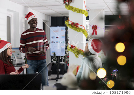 Multiethnic business team enjoying job shift break, bonding together in festive decorated office during winter holiday season. Coworkers feeling Christmas spirit mood, relaxing in xmas adorn workspace Multiethnic business team enjoying job shift break, bonding together in festive decorated office during winter holiday season. Coworkers feeling Christmas spirit mood, relaxing in xmas adorn workspace 108171906