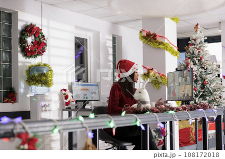 Asian manager in online videocall with employees during holiday season. Workaholic business executive wearing festive clothing, chatting with workers in teleconference meeting 108172018