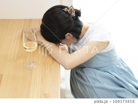 突っ伏す妊婦女性と白ワインがはいったワイングラス 108173818