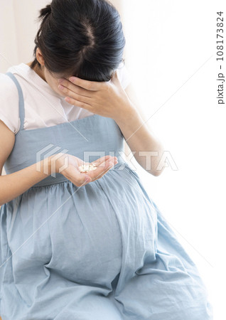 頭を抱えている女性が薬を持っているイメージ 108173824