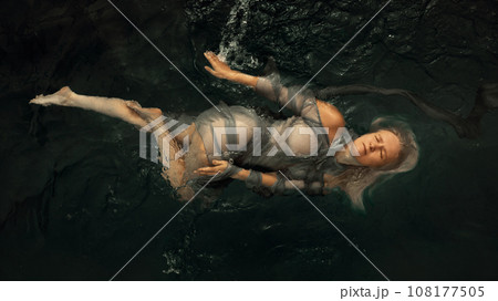 Portrait of a woman in a dress on a dark water surface Portrait of a woman in a dress on a dark water surface 108177505