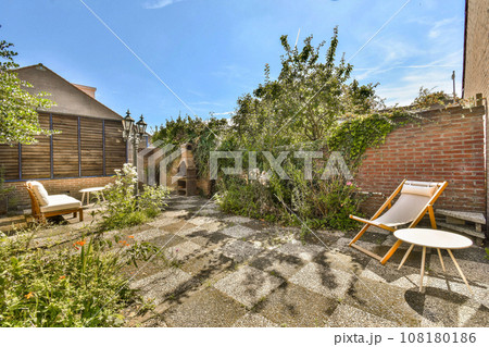 a backyard area with chairs and trees in the back, some plants growing on the ground next to the patio a backyard area with chairs and trees in the back, some plants growing on the ground next to the patio 108180186