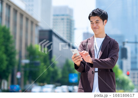 スマホを使ってオフィス街で働くミドルの男性のエンジニア 108180617