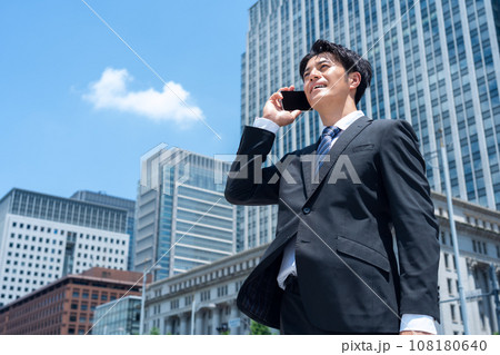 スマホを見ながらオフィスに通勤をするミドルのビジネスマン スマホを見ながらオフィスに通勤をするミドルのビジネスマン 108180640