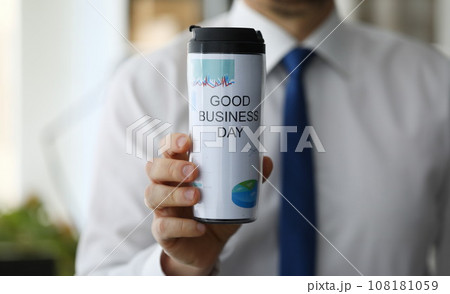 Man hold in hand thermal flask with hot beverage closeup Man hold in hand thermal flask with hot beverage closeup 108181059