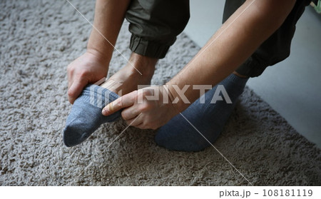 Man at home in morning puts gray socks on his leg Man at home in morning puts gray socks on his leg 108181119