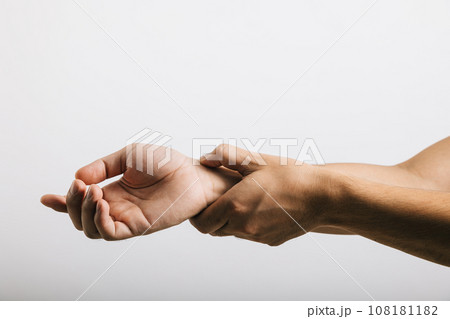 A sad Asian man, expressing discomfort due to wrist pain, possibly caused by carpal tunnel syndrome. Studio shot isolated on white, highlighting health care and medical issues. 108181182