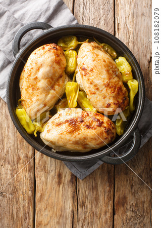 Baked chicken fillet with pepperoncini pepper close-up in a frying pan. Vertical top view 108182079