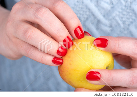 Woman's nails with manicure pierced the peel of an apple. Woman's nails with manicure pierced the peel of an apple. 108182110