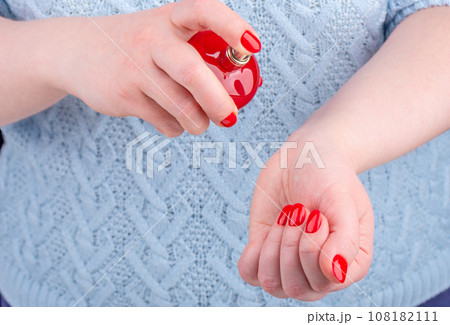 A young woman sprays perfume on her wrist. A young woman sprays perfume on her wrist. 108182111