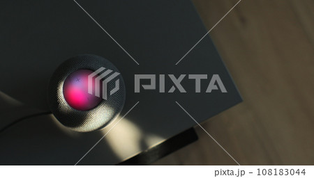 HomePod Mini speaker - the smart speaker is reacting to voice listening to human commands on the bedside table in the bedroom. Concept of a smart home. HomePod Mini speaker - the smart speaker is reacting to voice listening to human commands on the bedside table in the bedroom. Concept of a smart home. 108183044