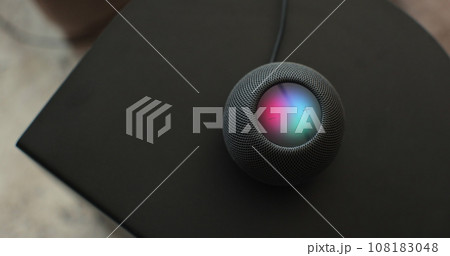 Using an HomePod Mini speaker - the smart speaker is reacting to voice listening to human commands and signalling its attention by the changing lights. Concept of a smart home. 108183048
