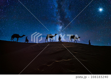 Christmas Jesus birth concept - Adoration of the Magi, Three Wise Men, Three Kings, and the Three biblical Magi with camel silhouettes journeying in sand dunes of desert follow Bethlehem star at night 108183240