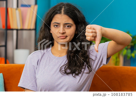 Upset Arabian woman showing thumbs down, dislike bad work, disapproval dissatisfied feedback at home 108183785