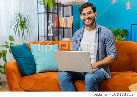 Young man freelancer sitting on couch close laptop pc after finishing work in living room at home Young man freelancer sitting on couch close laptop pc after finishing work in living room at home 108183815