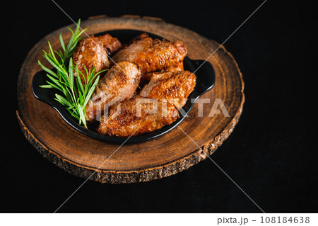 Semi-finished chicken wings on a dark background.Half-finished. Quick cooking at home. Fast food.Chicken wings fried until half cooked, semi-finished product.Semi-finished chicken wings lightly fried. 108184638