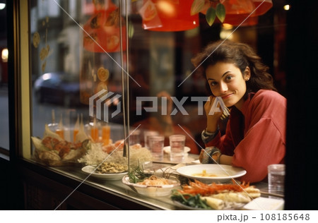 Woman sitting in cafe, seen through glass, eating sushi 108185648